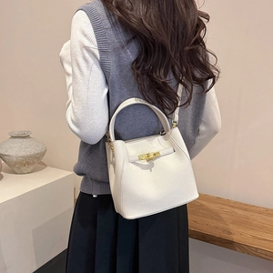 Detailed view of white lychee leather bucket bag featuring a gold metal twist lock
