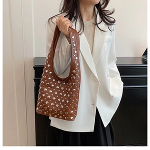 Détail d'un sac hobo marron en cuir avec rivets métalliques porté par un mannequin