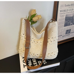 Close-up of a woven floral hollow-out tote bag with an adjustable brown leather strap