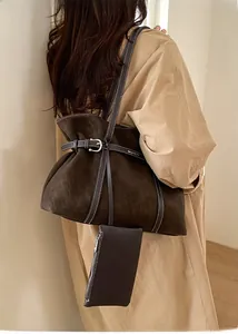 Detail view of large dark brown suede tote bag featuring white contrast stitching and sub-pouch