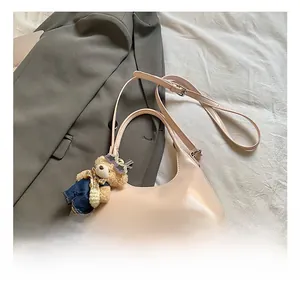 Detail of light pink glossy underarm bag with cute denim teddy bear keychain charm