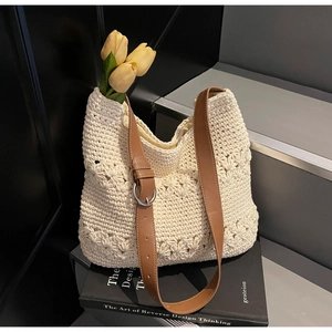 Detail of cream woven tote bag with brown leather strap and decorative hollow flower patterns
