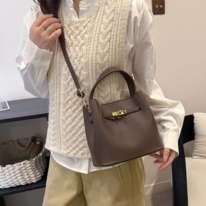 Detail of dark brown pebble leather bucket bag with golden twist lock and shoulder strap