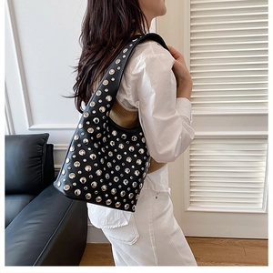 Detail of black leather underarm bag featuring silver rivets on a model's shoulder