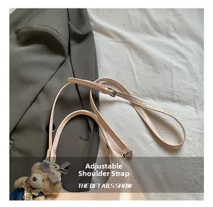 Detail showing the adjustable leather shoulder strap with metal buckle and bear charm