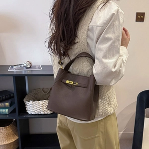 Detail view of the brown lychee grain leather bucket bag with a gold metal turn-lock