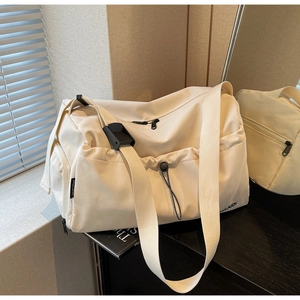 Detail of cream large capacity travel bag showing the adjustable strap and drawstring pocket