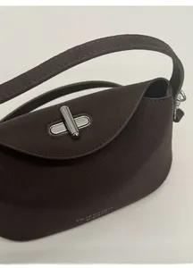 Detailed close-up of dark brown lychee leather bag with silver metal twist lock buckle