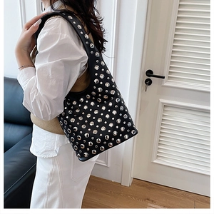 Detail of black leather hobo bag featuring silver punk rivets on a shoulder strap