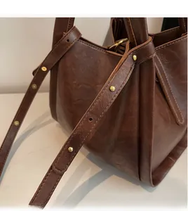 Detail of caramel PU leather shoulder bag featuring vintage texture and gold rivet studs