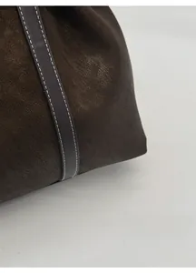 Detail of dark brown matte leather tote with white stitching and vintage texture