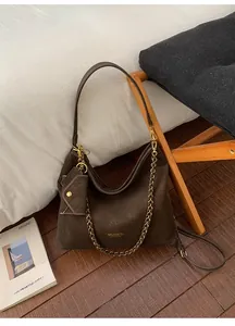 Close-up of retro brown suede hobo bag featuring metal chain and mini envelope pouch