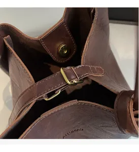 Detail of brown textured leather bucket bag featuring bronze hardware and magnetic closure