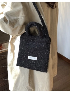 Black wool bucket bag with white snowflake texture and rectangular woven label