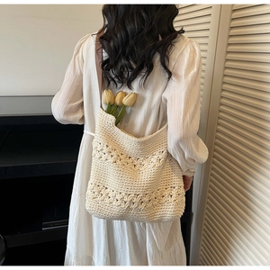 Detail of bohemian cream woven tote bag with hollow flower pattern and brown leather strap