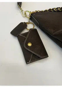 Close-up of deep brown leather tote detail with detachable envelope pouch and gold ring