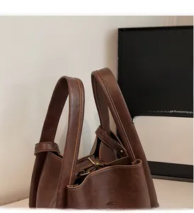 Close-up detail of reinforced handles and vintage leather texture on brown tote bag