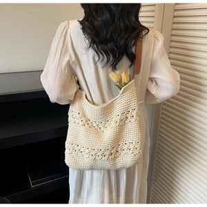Detail of crochet tote bag with hollow flower patterns and brown leather straps