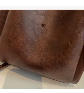 Close-up of vintage dark brown faux leather bag showing soft texture and embossed logo