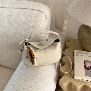 Detail of off-white lychee grain leather handbag with silver lock and wood bead charm
