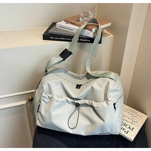 Detail of mint green travel bag featuring drawstring front pocket and dual zippers