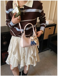 Detailed shot of pink patent leather handbag featuring a cute teddy bear charm accessory