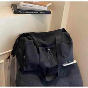 Close-up of black nylon travel bag featuring drawstrings and multiple storage pockets