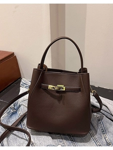 Deep brown lychee leather bucket bag with gold lock on denim jacket background