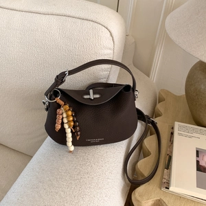 Detail of dark brown pebble leather doctor bag with silver twist lock and bead charm accessory