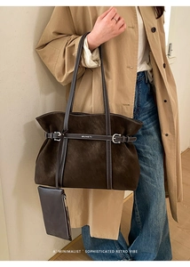 Detail of dark brown suede tote bag featuring white stitching and decorative belt