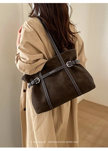Detail view of large brown suede tote bag with contrast stitching and metal buckle strap