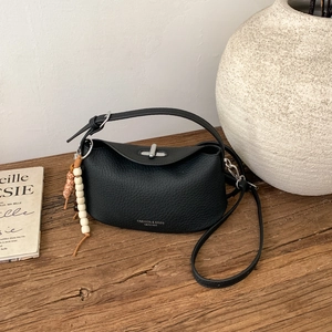 Detail of black pebbled leather dumpling bag with silver twist lock and beaded charm