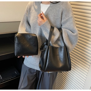 Detailed view of black glossy leather tote set with small pouch and metal logo mark