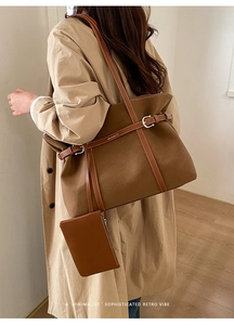 Detail of a brown canvas tote bag with leather straps and a matching small zipper pouch