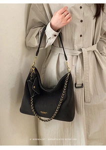 Close-up of black leather tote with gold chain strap and mini pouch on trench coat