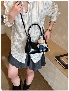 Close-up of black glossy crossbody bag featuring a cute teddy bear charm detail