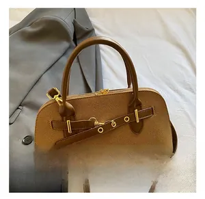 Détail du sac à main en cuir marron texturé avec garnitures dorées et doubles poignées