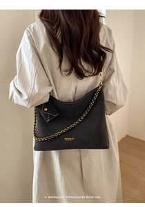Detailed back view of a black retro tote bag with chain strap on a model's shoulder