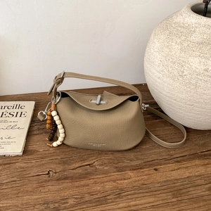 Detail of khaki green leather handbag with lychee texture and wooden bead charm accessory