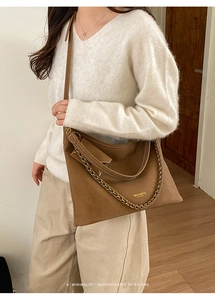 Detail of retro brown suede tote bag featuring metallic chain and MUHETI logo