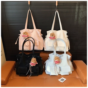 Macro shot of stylish tote bags in four colors with cute bear pendants on leather sofa