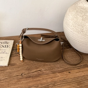 Close-up of dark brown lychee grain leather crossbody bag with wooden bead charm