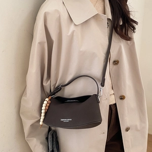 Detail of dark brown pebble leather bag with wooden bead charm and crossbody strap