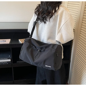 Detail of black large travel bag showing drawstring closure and adjustable shoulder strap