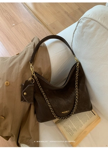 Detail of dark brown suede tote bag with gold chain strap and mini coin purse charm
