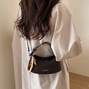 Detail of dark brown pebble leather handbag featuring vintage beaded tassel accents