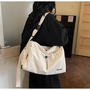 Adjustable wide black shoulder strap detail on a large cream canvas travel bag