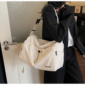 Detail view of large cream travel bag with drawstring design and adjustable strap