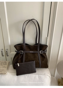 Detail of dark brown suede tote bag with contrast stitching and silver metal buckle