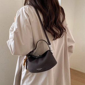 Detail of dark brown leather crossbody bag with lychee texture and wooden bead charm
